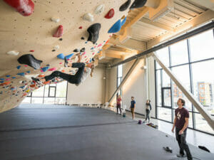 Frau klettert unter Aufsicht eines Trainers