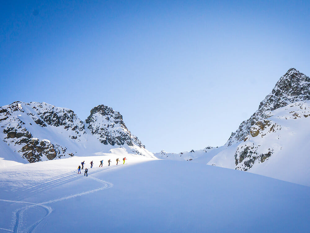Eine Gruppe Skitourengänger meandert sich den Berg hinauf.