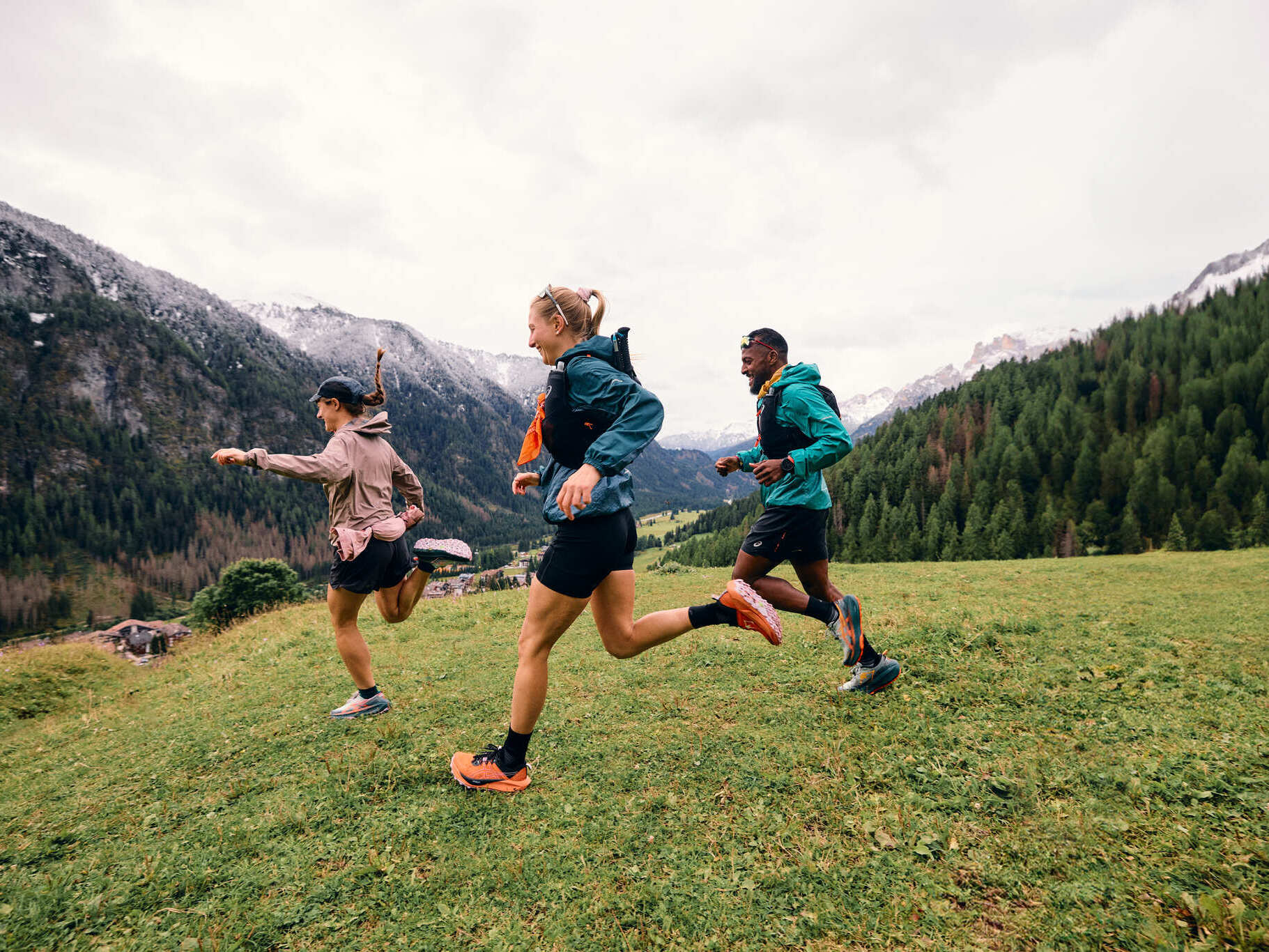 Drei Trailrunner rennen über eine Wiese