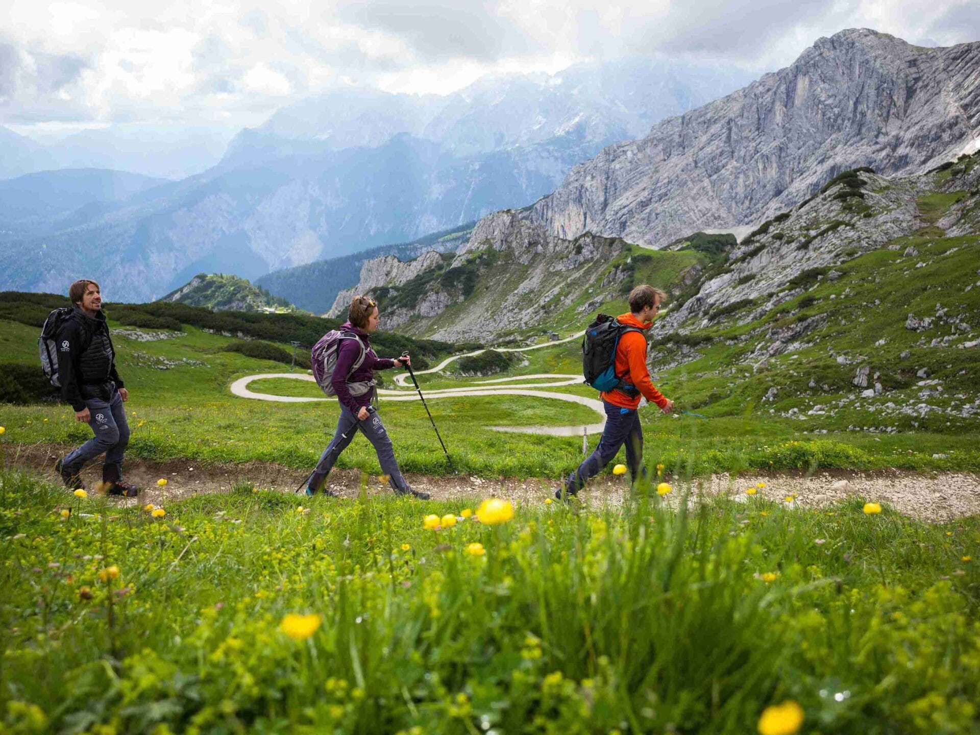 Drei Wanderer auf dem Weg zur Zugspitze mitten in der Natur und mit Bergen im Hintergrund