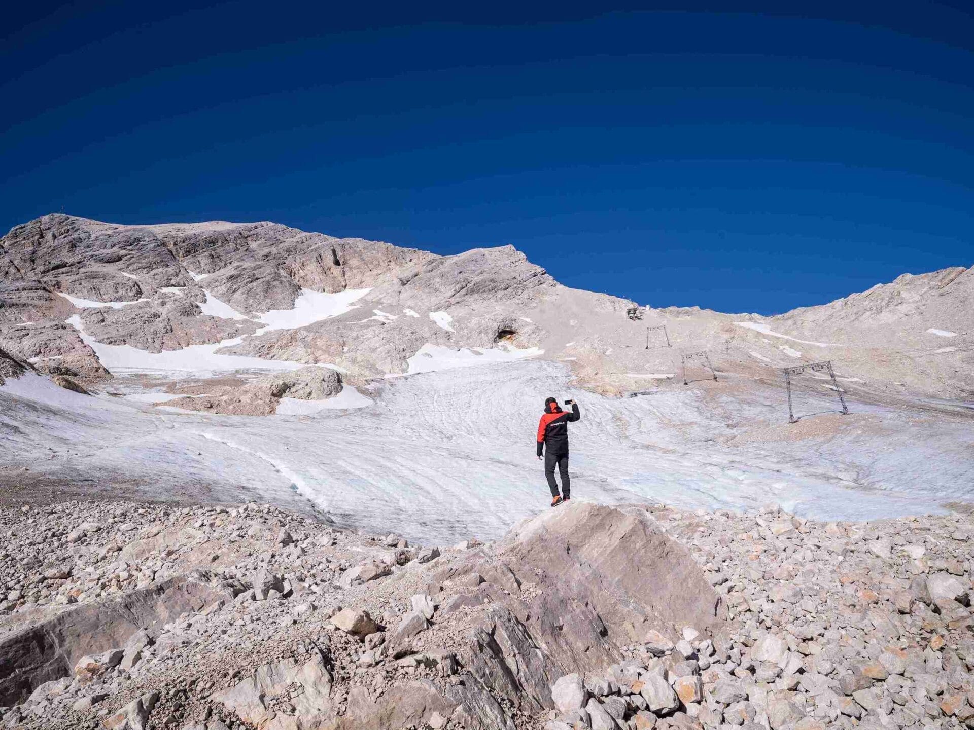 Ein Wanderer auf dem Schneeferner Gletscher mit Bergen und blauem Himmel im Hintergrund