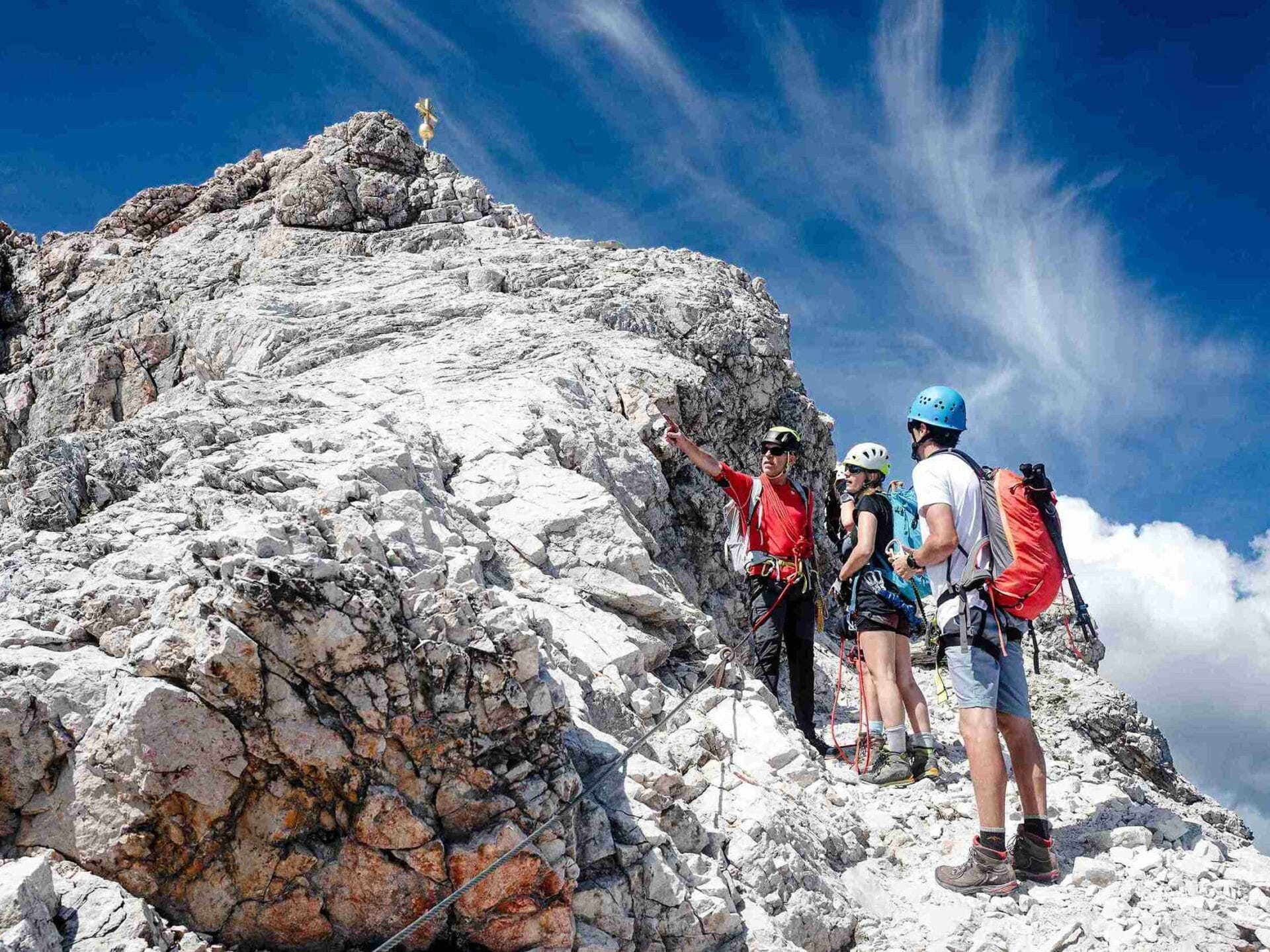 Drei Wanderer kurz vor ihrer Ankunft auf dem Gipfel mit der Bergspitze im Hintergrund