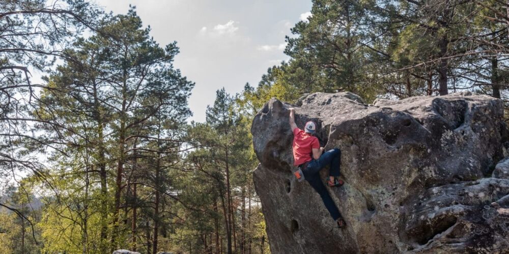 Mann klettert am Felsen im Fontainebleau.